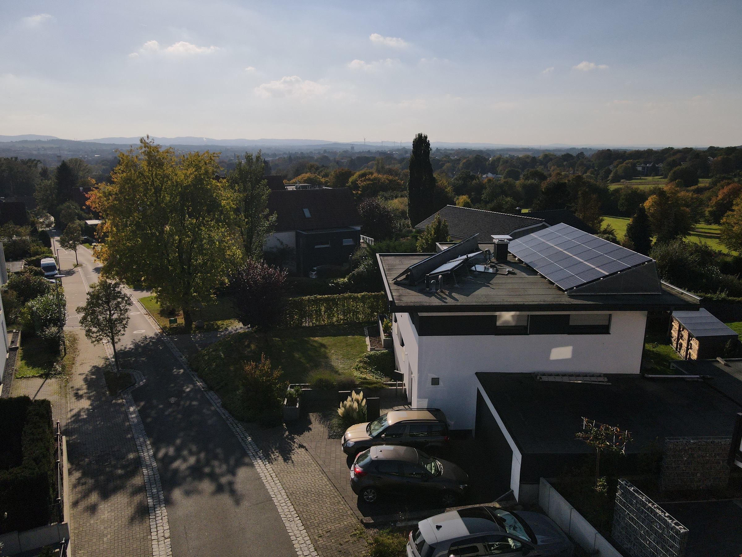 Modernes weißes Flachdachhaus mit Photovoltaik, umgeben von Grün, Blick über Lemgo